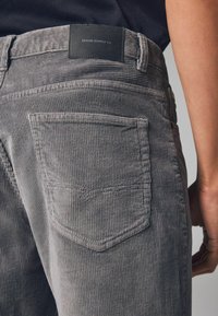 Szare spodnie z korduru o teksturowanej powierzchni, z skórzaną metką z napisem "DENIM SUPPLY CO" i designem tylnej kieszeni.
