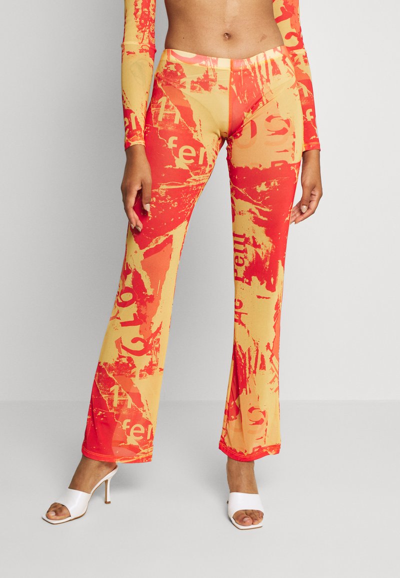 Calças flared elásticas com um padrão abstrato vibrante em vermelho e amarelo, apresentando uma textura suave e uma silhueta ajustada.