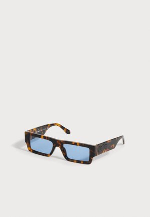 Lunettes de soleil rectangulaires en écaille avec verres teintés bleus et montures épaisses, présentées en angle sur un fond clair uni.