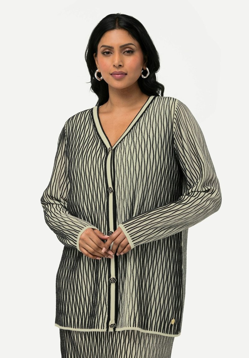 Mustat ja valkoiset ribbikardiganit, joissa on V-pääntie, pitkät hihat ja napit, joissa on kukkakoristeet.