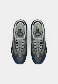 Par tenisica za trčanje New Balance 1000 u sivoj i tamnoplavoj boji s svijetloplavim vezicama, vidljivim logotipima branda i mrežastim detaljima, prikazano iz ptičje perspektive.