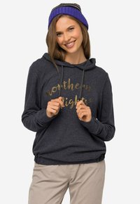 Mørkegrå hættetrøje med en guld, kursiv skrift, der står "northern lights." Modellen holder om manchetterne og bærer en lilla strikket beanie.