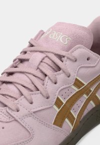 Sapatilha de camurça rosa com detalhes em castanho e marfim. Inclui atacadores redondos, colarinho acolchoado e uma sola exterior de borracha texturizada. Logótipo na língua.