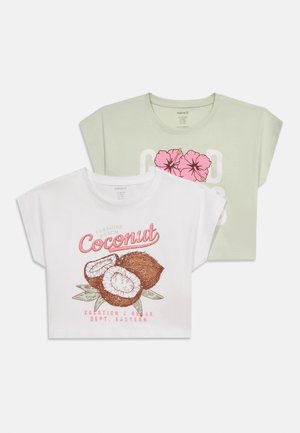 Két rövid ujjú crop top, az egyik fehér kókusz grafikával és rózsaszín szöveggel, a másik világos zöld rózsaszín hibiszkusz virágokkal és fehér szöveggel.