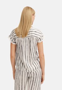 Gestreifte Bluse in Weiß mit schwarzen vertikalen Linien, kurzen aufgerollten Ärmeln und einem gerafften Design auf der Rückseite. Glattes, leichtes Material.