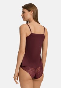 Burgundowa koszulka na ramiączkach z regulowanymi paskami i koronkowymi majtkami z kwiatowym wzorem. Gładka faktura, dopasowany krój oraz warstwowy detal w designie.