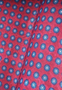 Tkano z różowym tłem z wzorem niebieskich kół, z białym punktem w środku każdego; gładka tekstura.