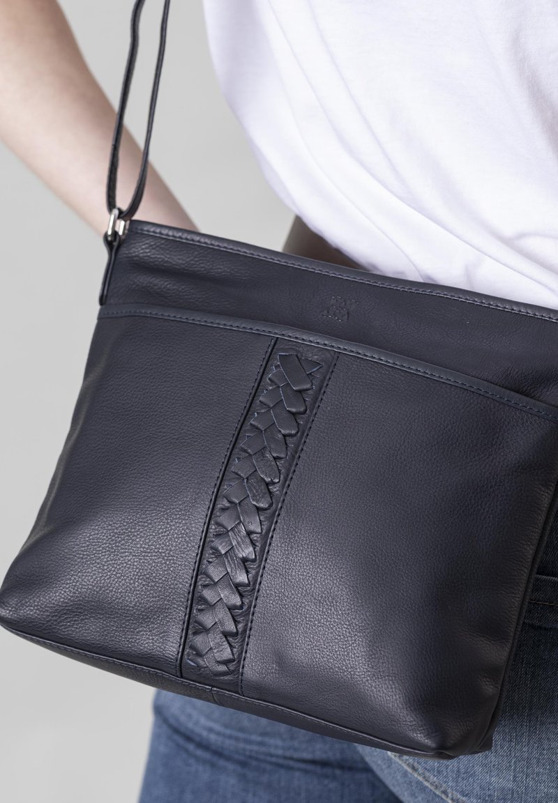 Navy leather crossbody bag with a woven detail in the center, a flat design, and an adjustable strap. Textured surface with subtle sheen.
