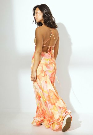 Flowy maxi-kjole i blødt stof med et farverigt blomsterprint i orange og pink, med krydsede stropper og en bundet ryg.