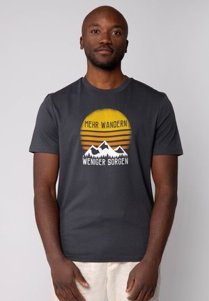 Graues Kurzarm-T-Shirt mit einem grafischen Design von Bergen, einer Sonne mit Streifen und dem Text "MEHR WANDERN WENIGER SORGEN" in Weiß und Gelb.