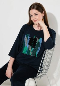 Navyblaue, übergroße T-Shirt mit einem strukturierten, gestickten Design in Grün, Schwarz und Blau. Weicher Baumwollmischstoff.