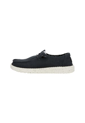 Scarpe di tela blu scuro con suola maculata bianca. Le caratteristiche includono un design minimalista, punta arrotondata e chiusura con lacci.