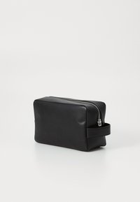 Svart kosmetikkveske i lær med rektangulær form, sølvglidelås og sidehåndtak for enkel bæring. Glatt tekstur med minimale detaljer.