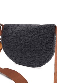 Borsa rotonda di un grigio scuro realizzata in pile testurizzato, con una cinghia marrone. Presenta un materiale morbido e peloso, una forma a mezza luna e un design semplice.