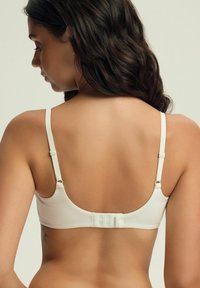 Biały biustonosz z drutem podtrzymującym wykonany z gładkiego materiału. Posiada regulowane ramiączka, zapięcie na haczyk oraz bezszwowy design z miękkimi krawędziami.