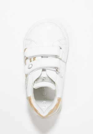 Hvid sneakers med dobbelte velcro-stropper, metallisk guldaccent, glat tekstur og et iriserende panel på siden. Rund tådesign.