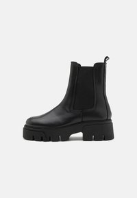 Botas de cuero negras hasta el tobillo con paneles laterales elásticos, punteras redondas y suelas de goma gruesa con surcos pronunciados para mayor tracción.