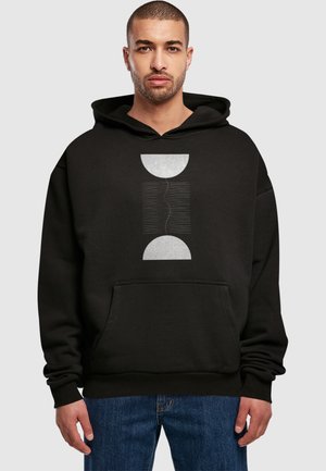 Schwarzer Hoodie mit einem zentralen Grafikdesign in Weiß und Silber, das eine kreisförmige Form und wellenförmige Linien zeigt, sowie einer vorderen Kängurutasche.