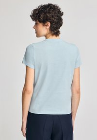 Ljusblå kortärmad T-shirt med rund halsringning och avslappnad passform, tillverkad av mjukt tyg som visar en slät textur och minimala detaljer.