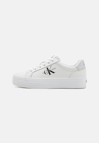 White sneakers with a smooth synthetic upper, elevated platform sole, and a black Calvin Klein Jeans logo on the side.
