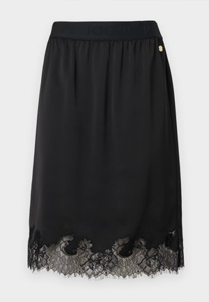 Schwarzer Rock aus weichem Stoff mit Spitzenbesatz am Saum, gestaltet mit einem gerafften Bund und einem goldenen Logo-Akzent.