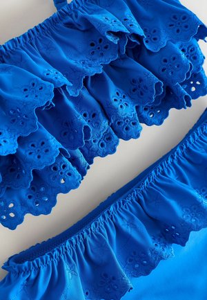 Mėlynas dviejų dalių maudymosi kostiumėlis su raukiniais, akių siuvinėjimu ir elastinėmis juostelėmis. Lygus audinys ryškios spalvos ir detaliai išdirbtu dizainu.