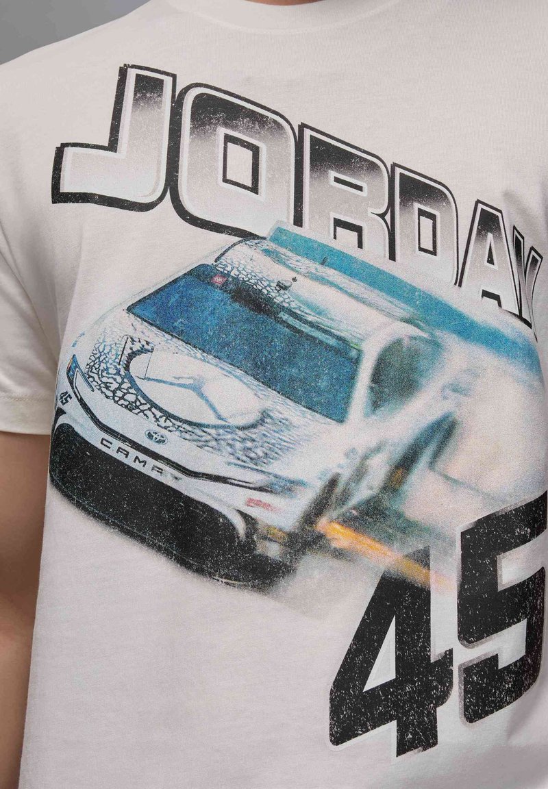 T-shirt bianca in cotone con una grafica di un'auto da corsa, con i numeri "45" e "JORDAN" in grassetto nero, in una gamma di colori blu e grigio.