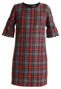 Robe à carreaux en gris, rouge et jaune avec des manches évasées et une coupe droite. Elle possède une fermeture éclair au dos et des détails en frange sur les manches.
