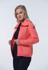 Gevoerde koraalkleurige jas met een gestructureerde kraag, volledige ritssluiting en contrasterende roze accenten op de mouwen en onderkant. Heeft een geometrisch patroon.