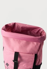 Ροζ υφασμάτινο σακίδιο με μαύρο ιμάντα πόρπης, ανοιχτό στην κορυφή που δείχνει τη φόδρα εσωτερικά σε απλό λευκό φόντο.