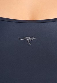 Maillot de bain bleu marine au texture lisse, avec une petite broderie de kangourou argentée à l'avant, ajoutant un détail subtil au design.