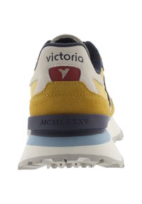 Sneaker con suede giallo e blu navy, intersuola bianca, suola in gomma testurizzata e logo 'victoria' sul retro. Accentuata con un dettaglio rosso.
