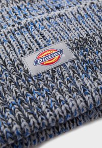 Γκρι πλεκτό σκουφάκι με μπλε λεπτομέρειες, υφασμάτινο σχέδιο και ετικέτα με το λογότυπο "Dickies" ραμμένο πάνω του.