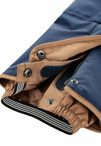 Wasserabweisende Jacke mit einem dunkelblauen Oberteil, braunem Unterteil, elastischen Bündchen, Druckknöpfen und einer Reißverschlusstasche.