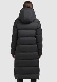 Schwarze Pufferjacke mit gepolstertem Design, langer Länge und großer angenähter Kapuze. Verfügt über einen Reißverschluss am Boden und elastische Bündchen.
