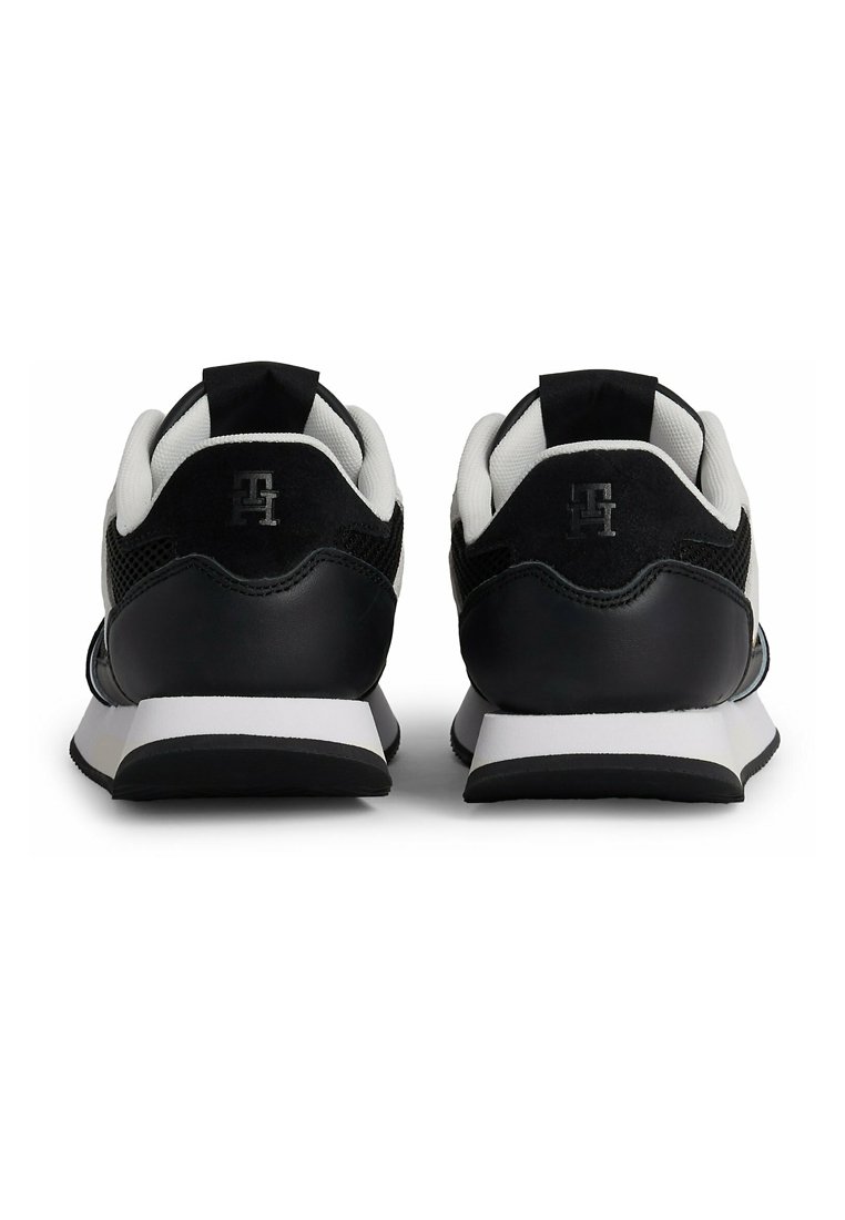 Zapatillas deportivas en blanco y negro con parte superior de malla y detalles de cuero, suela acolchada y logotipo en el talón.