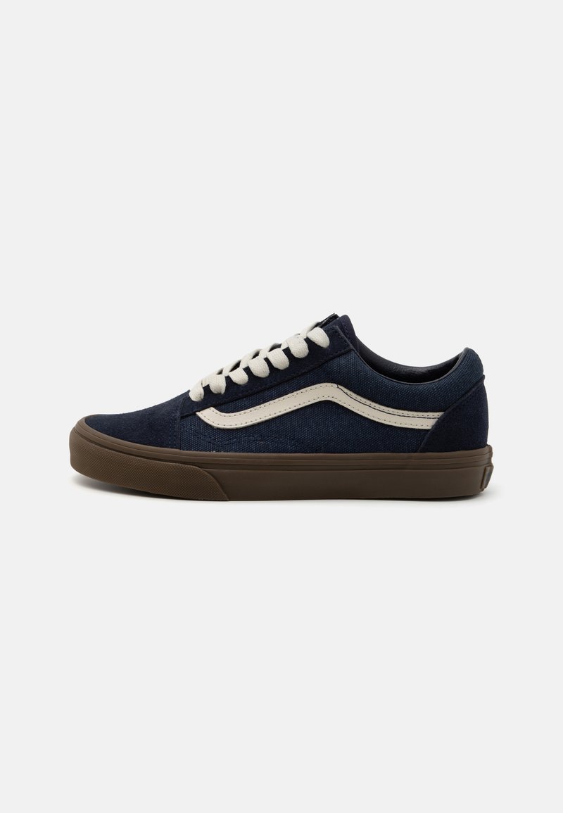 Marineblå kanvassneakers med en hvit sidestripe, rund tå og brun gummisåle. Har hvite snørebånd og polstret krage for komfort.