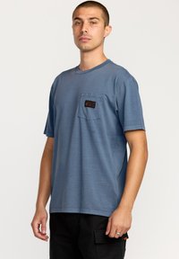 Lys bl�å kortærmet T-shirt lavet af blødt stof, med en brystlomme og mærke. Simpelt design med rund halsudskæring.