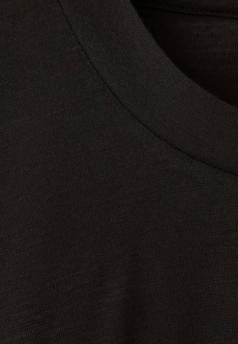 Black cotton t-shirt fabric, close-up view, featuring a round neckline and a smooth, slightly textured surface. No visible patterns.