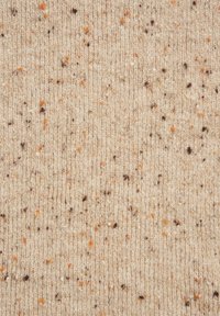 Strikket stof i beige med en tekstureret overflade, der har spredte brune og orange prikker. Ensartet ribbet design og blød struktur.