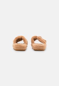 Faux fur slippers in light tan with two cross straps. Soft texture and padded sole. Flat bottom for stable wear.