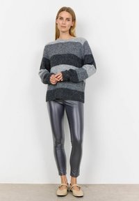 Sivi prugasti pulover s pahuljastom teksturom, uparen s sjajnim sivim tajicama. Ovaj outfit ima izrez u obliku srca i slobodan kroj.