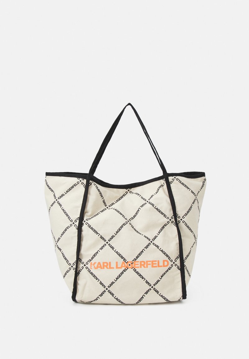 Canvas tote bag in beige with black diamond pattern and "KARL LAGERFELD" text. Features black trim and two shoulder-length straps.