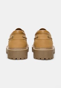 Scarpe in pelle marrone con suola in gomma spessa, dotate di fori per lacci, dettagli cuciti e design con punta arrotondata.