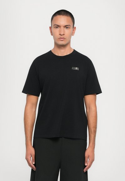 T-shirt noir en coton avec une coupe décontractée, encolure arrondie et petit design graphique sur la poitrine gauche. Manches courtes et texture lisse.