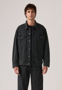 Μαύρο τζιν μπουφάν με κουμπιά μπροστά, δύο τσέπες στο στήθος και κάθετη ραβδωτή υφή. Μακριά μανίκια, άνετη εφαρμογή και ασημένια κουμπιά.