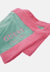 Asciugamano in cotone con un corpo verde e bordo rosa, con il testo ricamato "GUESS CAL. 1981". Texture morbida con una sensazione soffice.