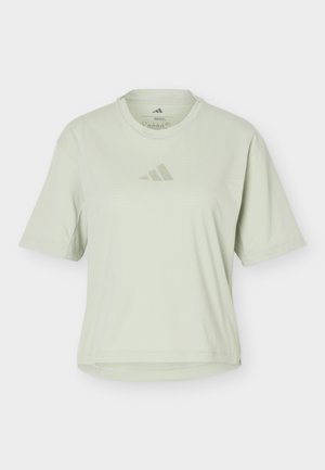 Hellgrünes T-Shirt mit kurzen Ärmeln und Rundhalsausschnitt, mit einem kleinen, tonalen Adidas-Logo mittig auf der Brust vor schlichtem Hintergrund.