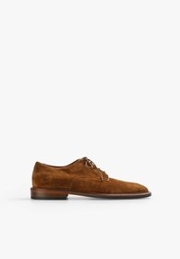 Zapato de vestir de ante marrón con punta redondeada, cierre con cordones y un bajo tacón de madera apilada. Textura suave con un detalle de costura mínimo.