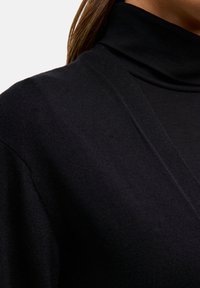 Czarny sweter z golfem, charakteryzujący się delikatnym splotem, dopasowanym krojem i głębokim dekoltem w kształcie litery V. Klasyczny i uniwersalny styl.